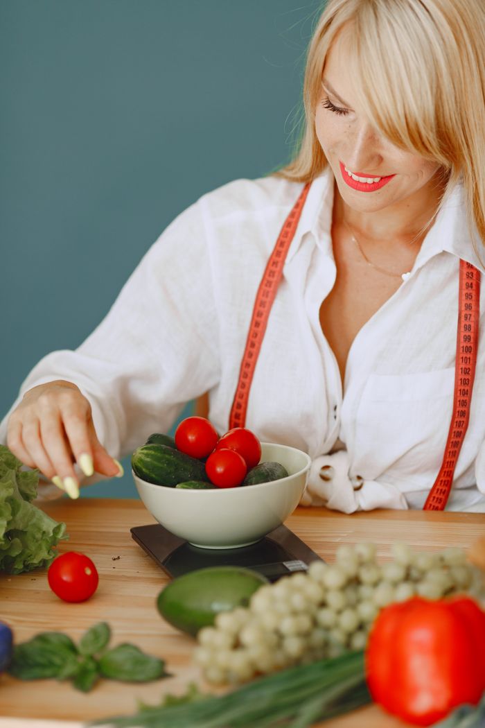 contact-img A nutritionist measuring fresh vegetables on kitchen scales for a healthy lifestyle.