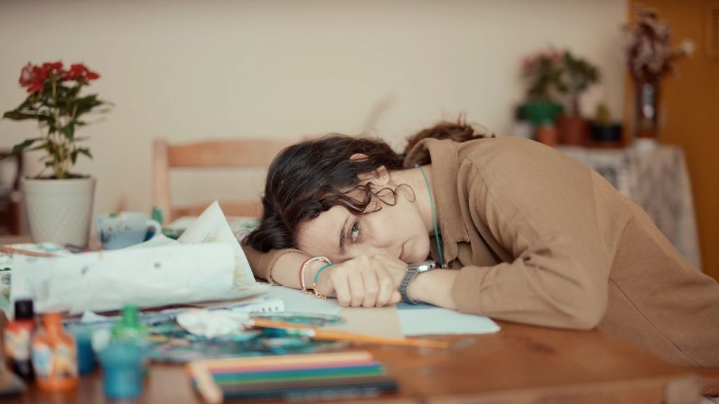 Una mujer echada sobre un escritorio, cansada y mentalmente agotada