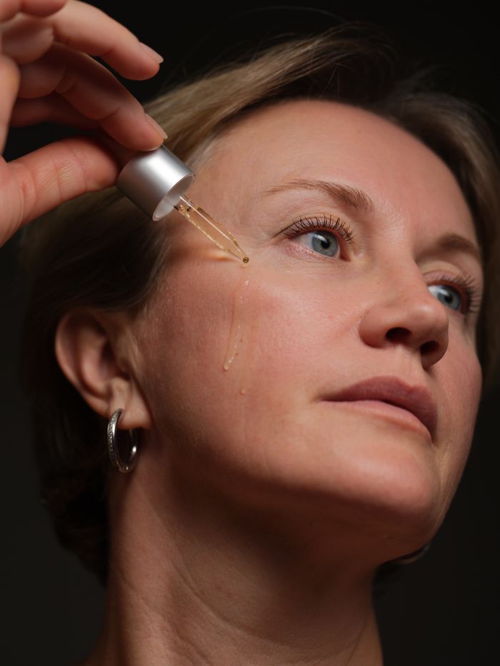 Mujer de mediana edad aplicándose sérum en la cara