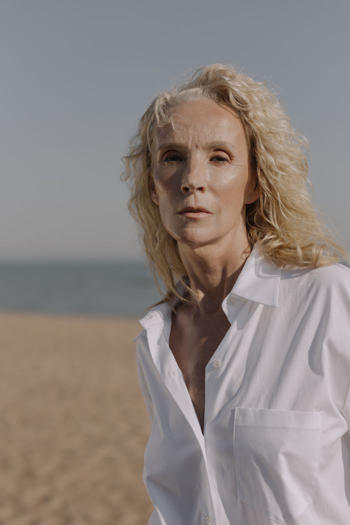Stylish senior woman with blonde hair posing gracefully on a sunny beach.