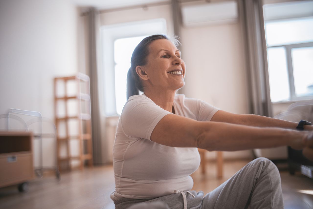 Happy senior woman exercising indoors, promoting active and healthy lifestyle.
