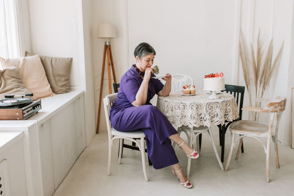 Mujer de más de 60 años tomando una taza de café y un trozo de tarta, feliz y serena