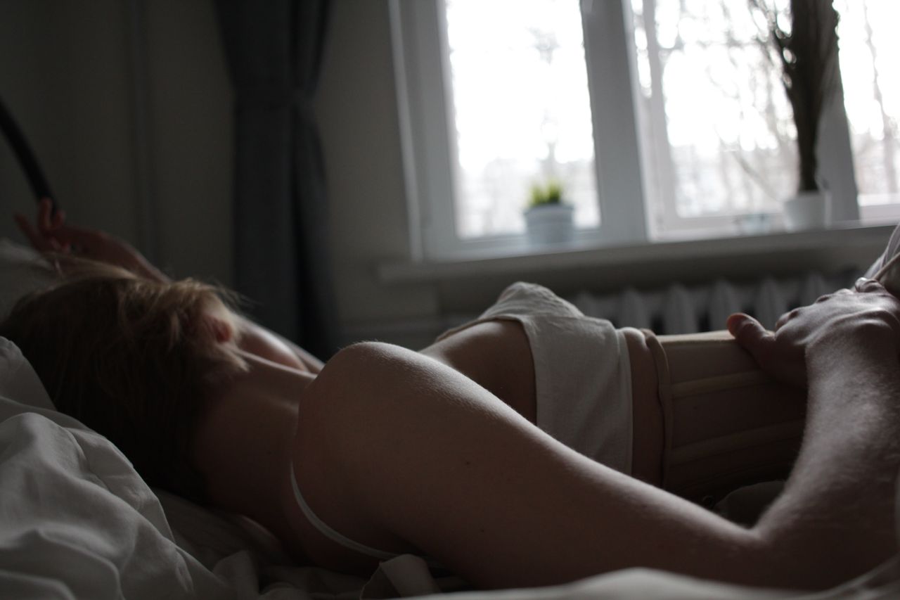 A serene scene of a woman resting in bed bathed in soft morning light.