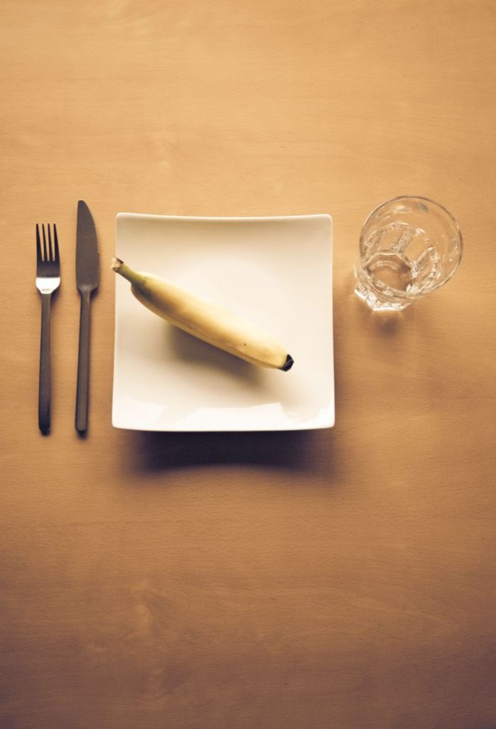 ¿Todo te sienta mal de repente? El motivo oculto por el que tienes digestión lenta en la menopausia Cena compuesta por un solo plátano en un plato, junto a un vaso de agua, un cuchillo y un tenedor