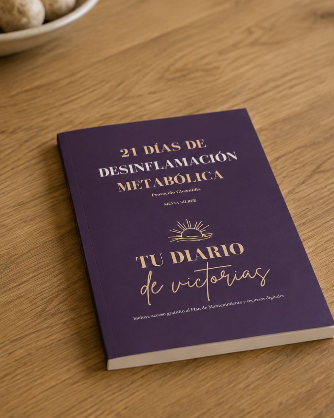 deja de improvisar con tu salud metabólica a partir de los 40: por qué necesitas un método y no otra lista de remedios sueltos Diario del método Glownidia en tapa dura sobre mesa de madera, con cuenco decorativo