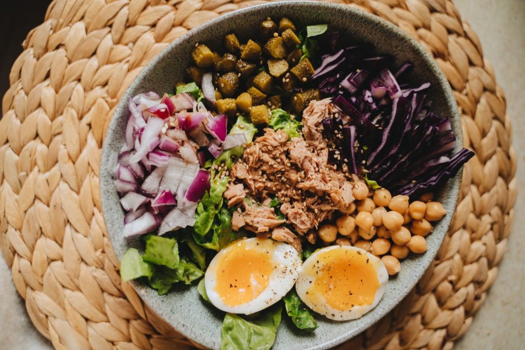Plato colorido y equilibrado con verdura, garbanzos, huevos cocidos, col, peinillos y atún.